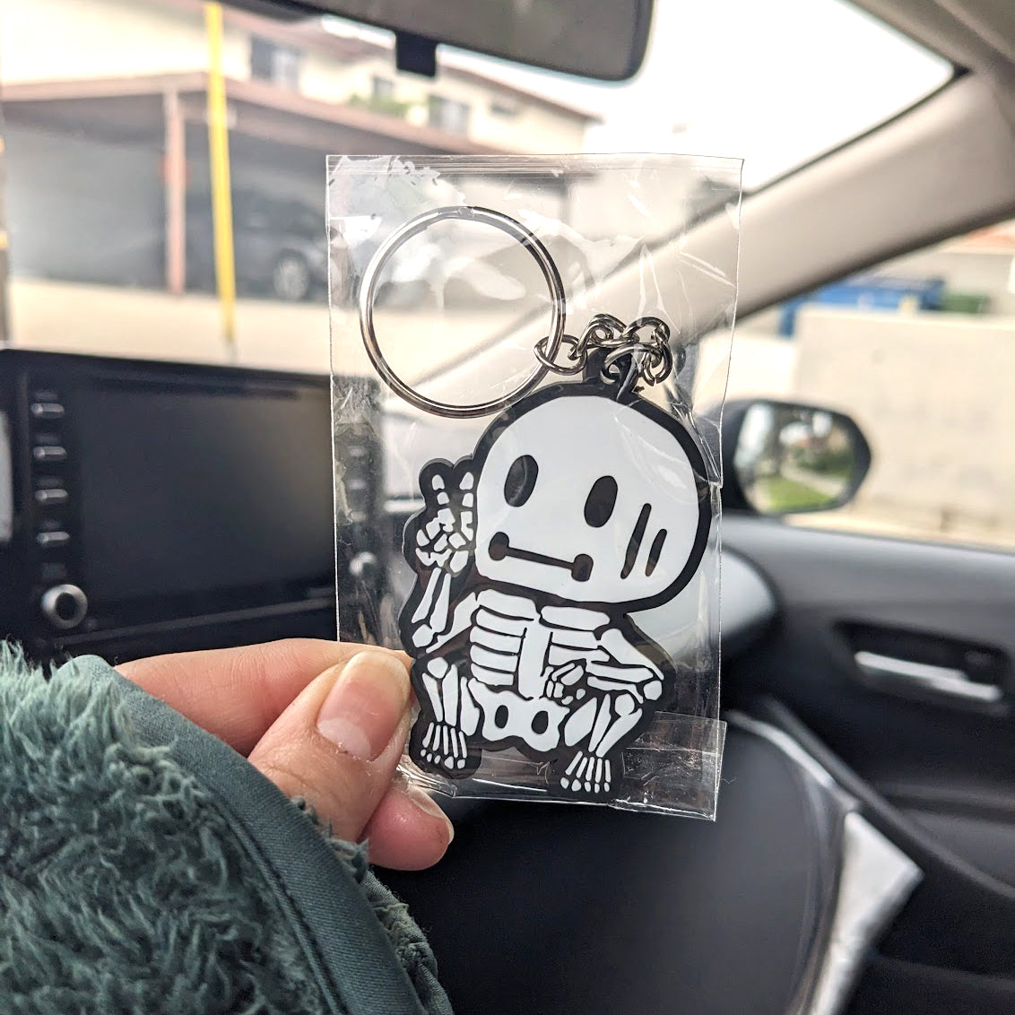 hand holding a skeleton skelemen black and white rubber strap keychain
